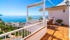 A balcony with a view of the sea, a table with chairs, and a potted plant. - Capistrano Playa 404 by Casasol (Nerja)