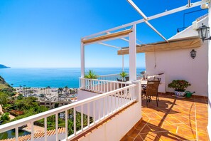 Ein Balkon mit Meerblick, einem Tisch mit Stühlen und einem Blumentopf.