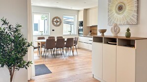 Una cucina moderna con zona pranzo, pavimento in legno e un'ampia finestra.