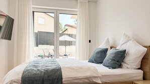 Una camera da letto con un letto, cuscini, un comodino e vista sull'esterno.
