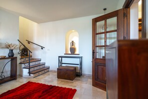 Eine Treppe mit einem roten Teppich, ein Tisch mit einer Vase und eine Holztür.