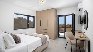 Ein modernes Schlafzimmer mit Bett, Schreibtisch, Stuhl, Kleiderschrank und einer Schiebetür, die auf einen Balkon führt.
