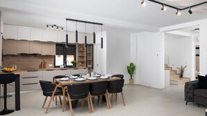 Eine moderne Küche mit Einbauküchenschränken, ein Essbereich mit Holztisch und schwarzen Stühlen sowie eine Treppe zu einer weiteren Ebene.