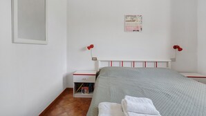 A bedroom with a bed, a nightstand, a wall-mounted lamp, and a poster on the wall.