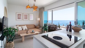 A modern living room with a sofa, coffee table, and a view of the ocean. - Bayview Hills Deluxe by Casasol (Torrox)