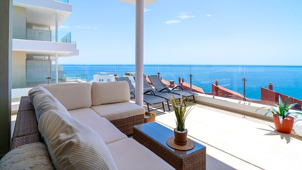 A modern balcony with a sofa, lounge chairs, and potted plants, overlooking a clear blue sea. - Bayview Hills Deluxe by Casasol (Torrox)