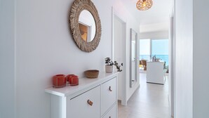 A modern hallway with a white console table, a woven mirror, and a hanging light fixture. - Bayview Hills Deluxe by Casasol (Torrox)