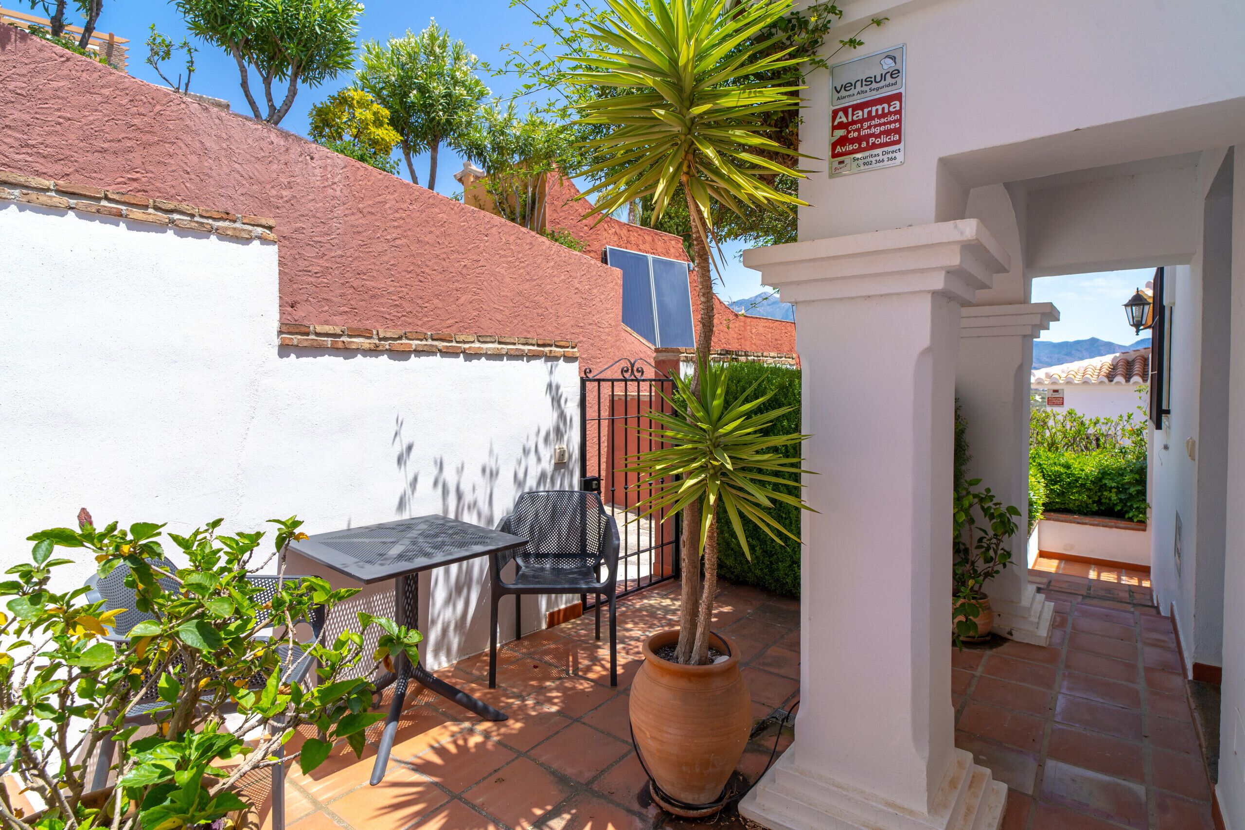 Un patio con mesa y sillas, una planta en maceta y un letrero que indica una alerta policial.