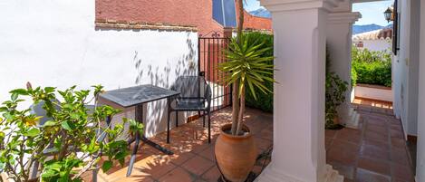 Un patio con mesa y sillas, una planta en maceta y un letrero que indica una alerta policial.