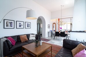 Ein modernes Wohnzimmer mit einer schwarzen Ledersofa, einem Holztisch und einem Essbereich im Hintergrund.