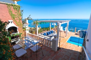 Eine Terrasse mit Pool, Sitzgelegenheiten im Freien und Blick auf den Ozean.