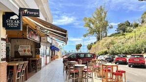 A restaurant with outdoor seating, a sign for 'The Steak House at Burriana', and a 'NerjAle' craft beer sign. - Casa Rosa Splash Pool by Casasol (Nerja)