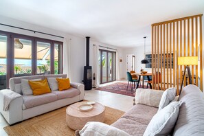Ein modernes Wohnzimmer mit einer Couch, einem runden Couchtisch und einem Essbereich mit Tisch und Stühlen.