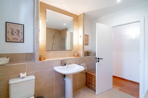 Ein modernes Badezimmer mit einem weißen Waschbecken, einem großen Spiegel und einer Dusche.