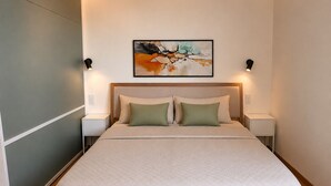 Une chambre à coucher moderne avec un grand lit, deux tables de chevet, une tête de lit et un tableau abstrait accroché au mur.