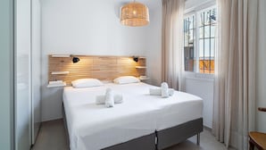 A modern hotel room with a large bed, a wooden headboard, a hanging light fixture, and a window with curtains. - Casa Solera by Casasol (Nerja)