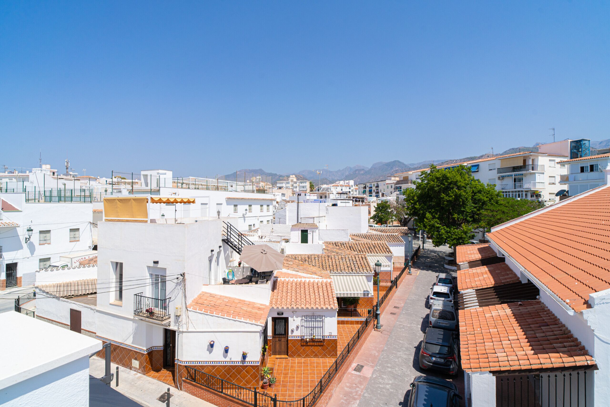 Un quartier résidentiel avec des bâtiments blancs, des toits recouverts de tuiles rouges et un ciel d’un bleu éclatant.