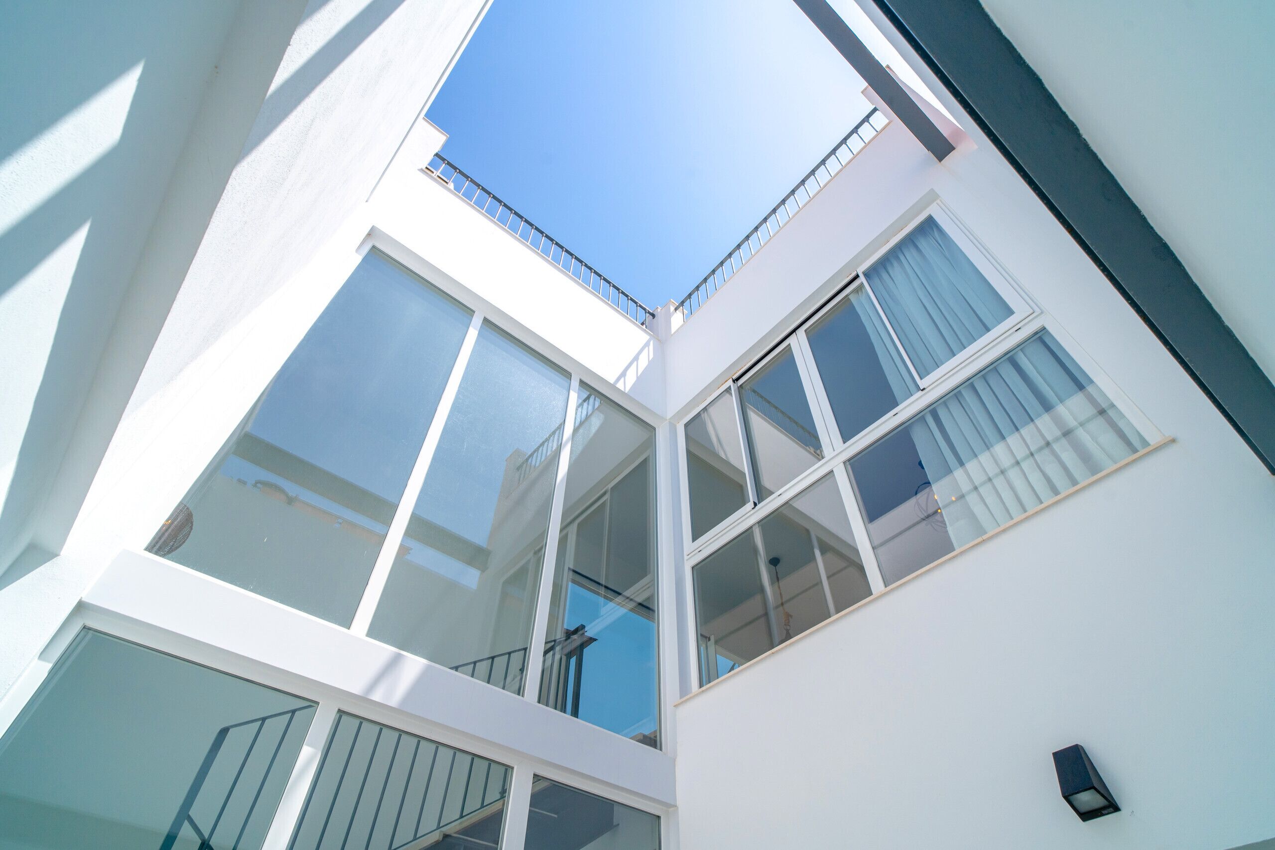A modern building with multiple floors, large windows, and a clear sky.
