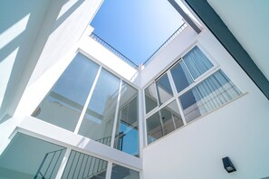Ein modernes Gebäude mit mehreren Stockwerken und großen Fenstern, strahlend blauer Himmel.