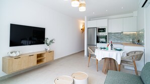 Ett modernt kök med vita skåp, en inbyggd ugn och en matplats med bord och stolar.