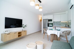 Eine moderne Küche mit weißen Schränken, einem eingebauten Backofen und einer Essecke mit Tisch und Stühlen.