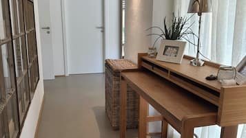 Un couloir avec un bureau en bois, un panier en osier et une lampe.
