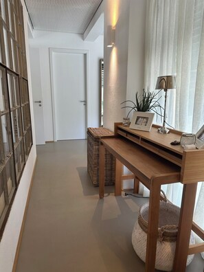 A hallway with a wooden desk, a wicker basket, and a lamp.