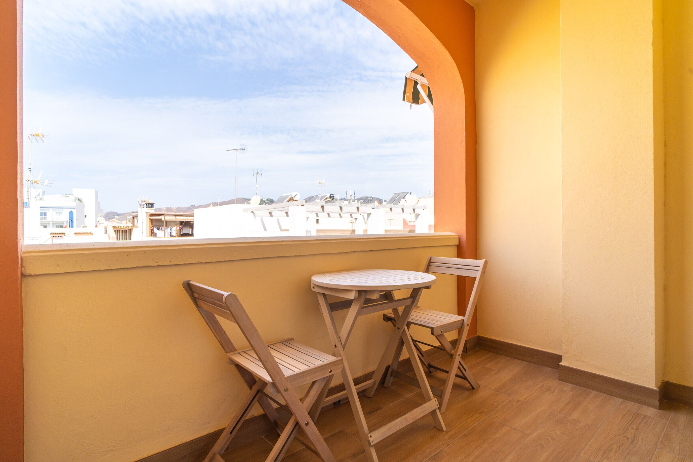 A balcony with two wooden chairs and a small round table.