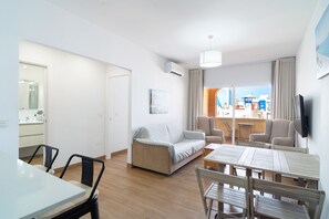 A modern living room with a sofa, chairs, a dining table, and a TV. - Toboso 2J Torrecilla Beach by Casasol (Nerja)