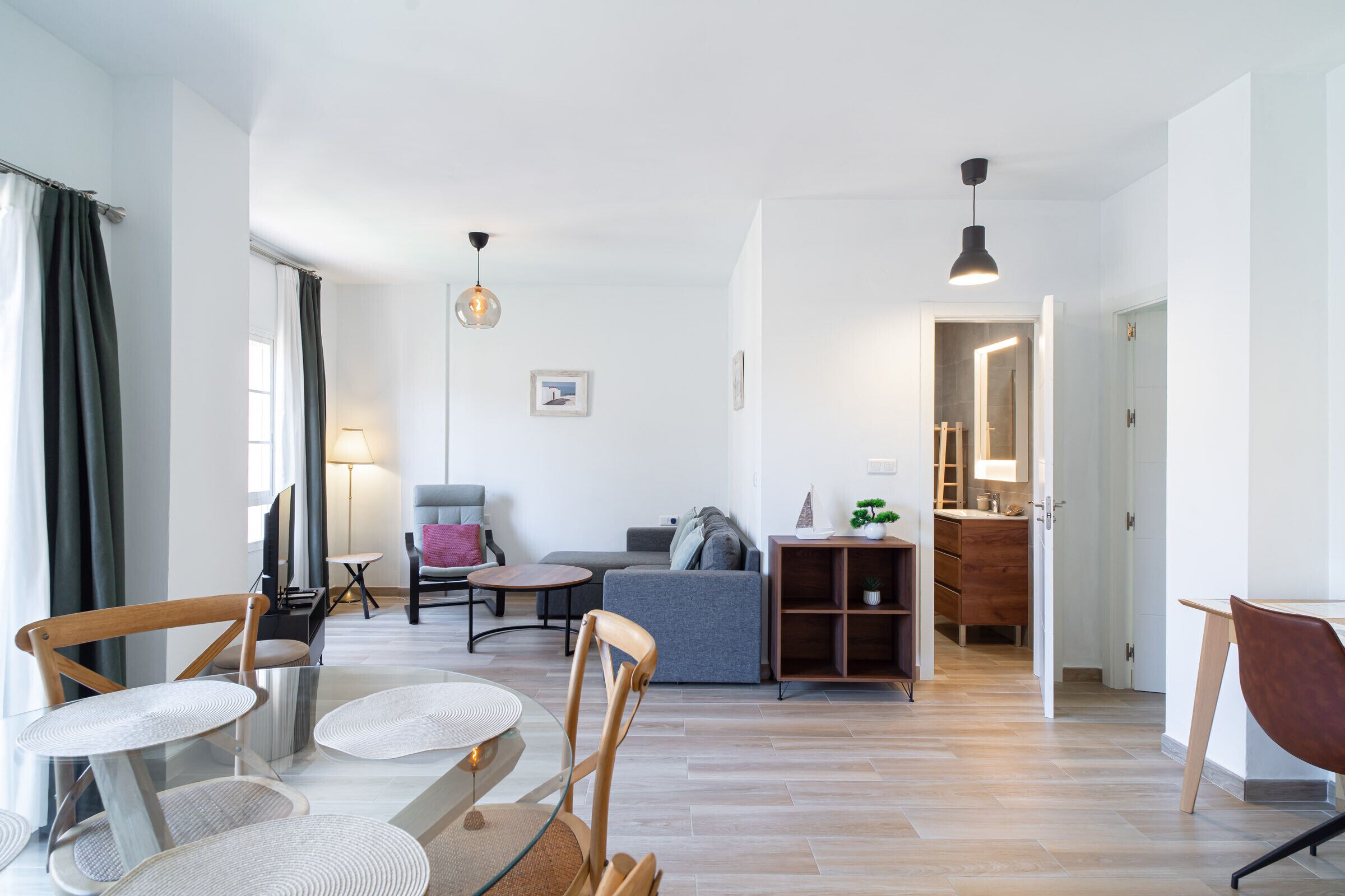 A modern living room with a sofa, chairs, a coffee table, and a dining area with a table and chairs.