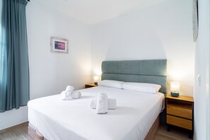 A hotel room with a bed, two bedside tables, a headboard, a wall-mounted picture, and a window with curtains. - Toboso 1R Beach Living (Nerja)