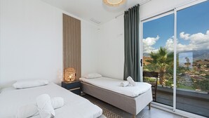 Een hotelkamer met twee bedden, uitzicht op de stad en een balkon met een stoel.