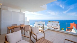 Een balkon met houten meubels en uitzicht op zee.