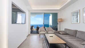 Een moderne woonkamer met een bank, een salontafel en uitzicht op zee door een schuifdeur.