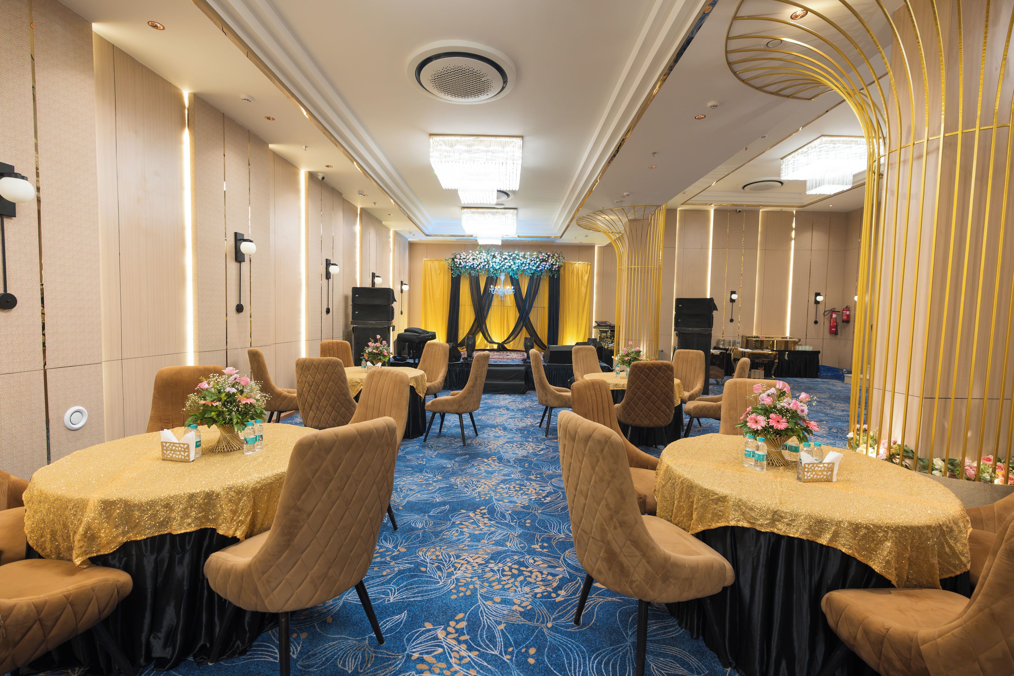 Uma sala de conferências de hotel com mesas redondas, cadeiras e carpete azul.