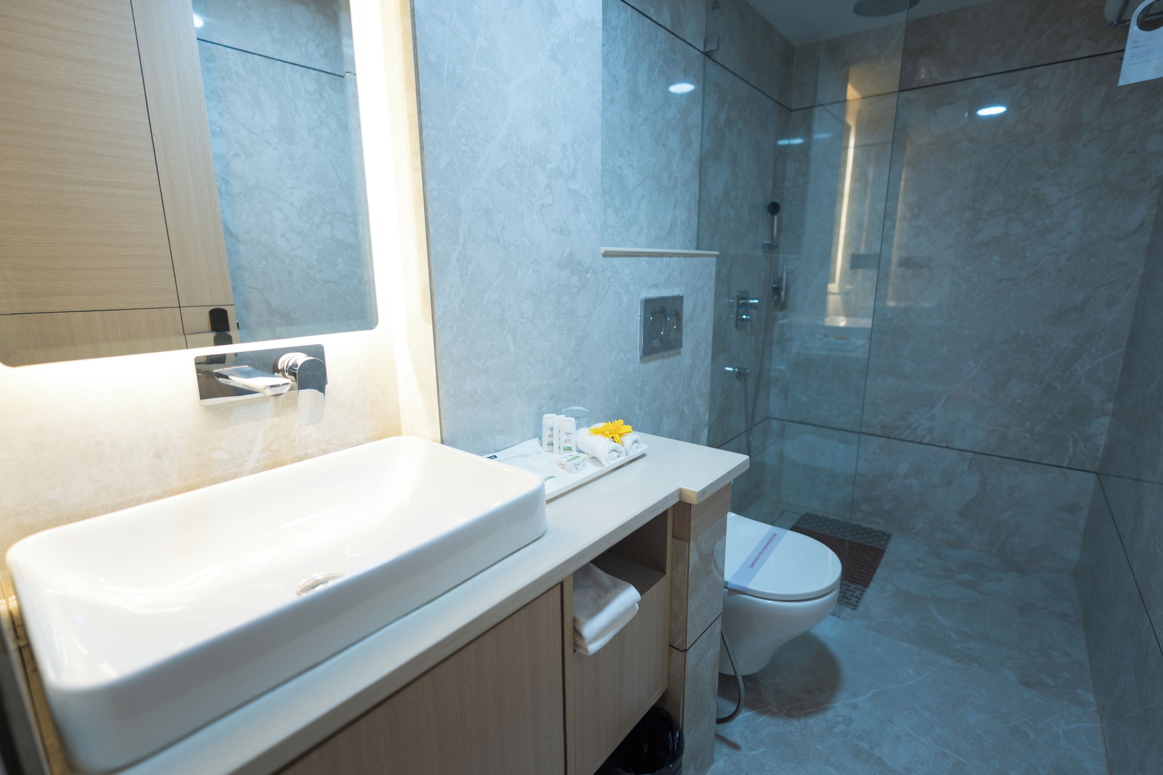 Un baño moderno con un lavamanos grande, espejo y cabina de ducha con mampara de vidrio.