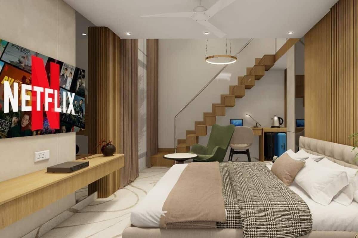 A modern bedroom with a bed, a desk, a chair, a TV, and a staircase.