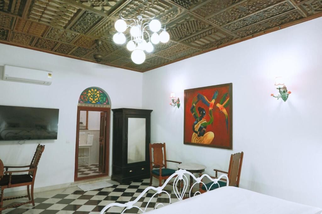 A room with a checkered floor, a bed, a television, a cabinet, and a painting on the wall.
