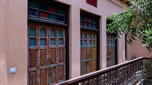 Un edificio con puertas de madera grandes y un balcón con barandilla de hierro forjado.