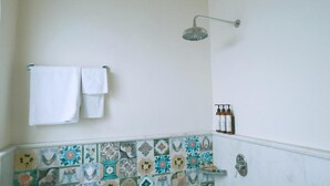 Un baño con ducha, paredes con azulejos y un perchero para toallas.