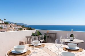 A table set for dining with a view of the sea and buildings in the background. - Casa Lavanda - Hacienda 37 by Casasol (Nerja)