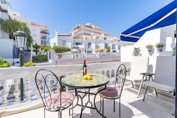 A terrace with a round table, chairs, and a bottle of wine. - Casa Lavanda - Hacienda 37 by Casasol (Nerja)
