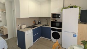 A compact kitchen with white cabinets, a microwave, an oven, a dishwasher, and a washing machine. - Bright apartment with a spacious terrace near the ocean. (Mazarrón)