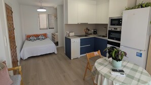 A compact room with a bed, a small kitchenette, a dining area with a table, and a chair. - Bright apartment with a spacious terrace near the ocean. (Mazarrón)