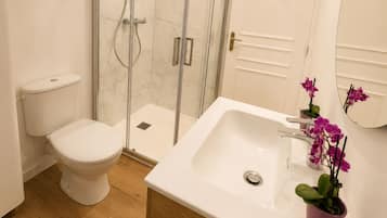Een douche, handdoeken, zeep, toiletpapier