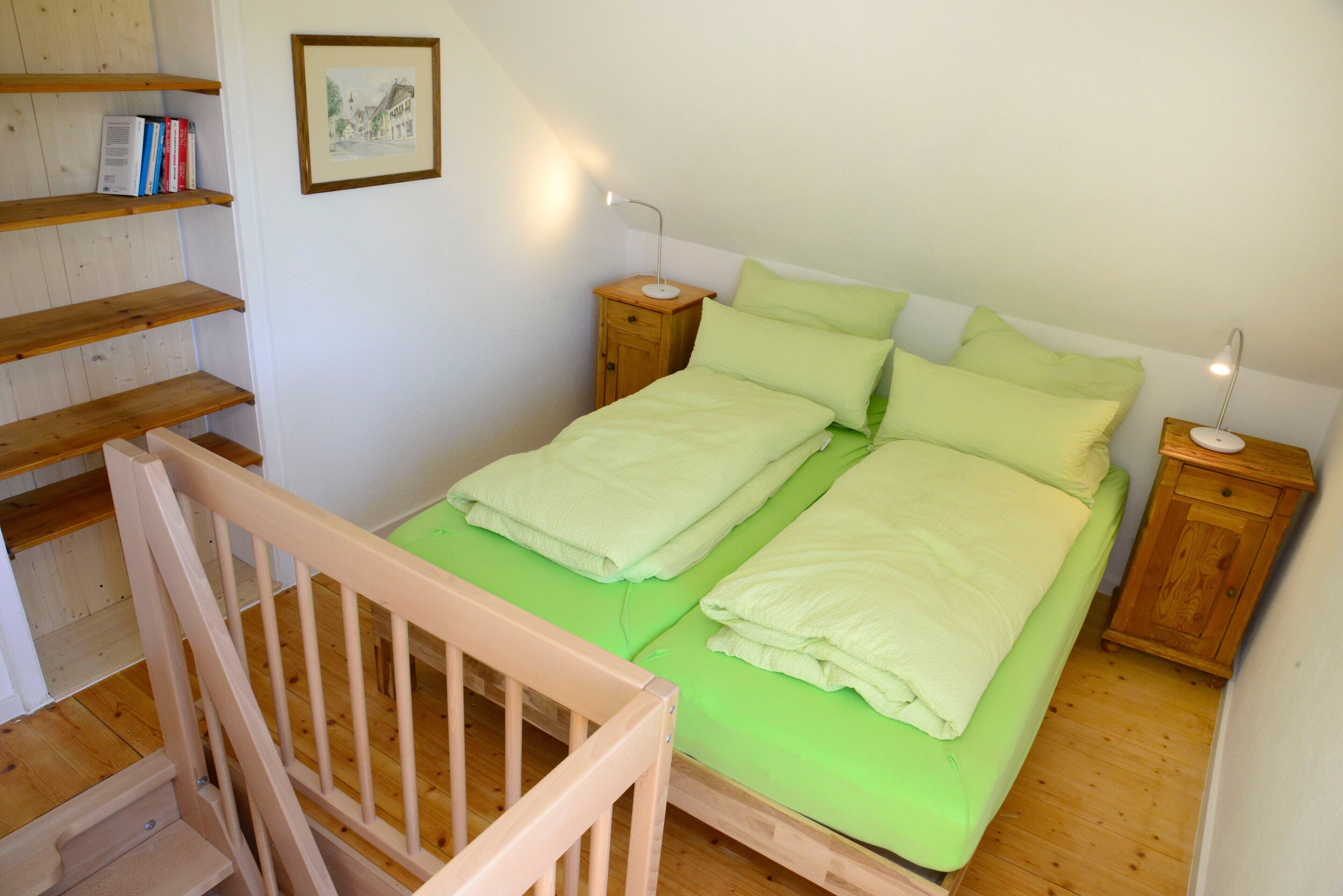 Une chambre à coucher avec un lit en bois, deux tables de chevet, une commode, un escalier en bois et une bibliothèque.