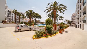 Un estacionamiento con un coche, palmeras y una piscina.