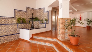 Un vestíbulo con paredes de azulejos, una fuente y plantas en macetas.