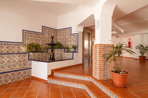 A lobby with tiled walls, a fountain, and potted plants. - Carabeo 52 Apartment by Casasol (Nerja)