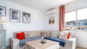Ein Wohnzimmer mit einer Couch, einem Couchtisch, Wandbildern und einer Klimaanlage.